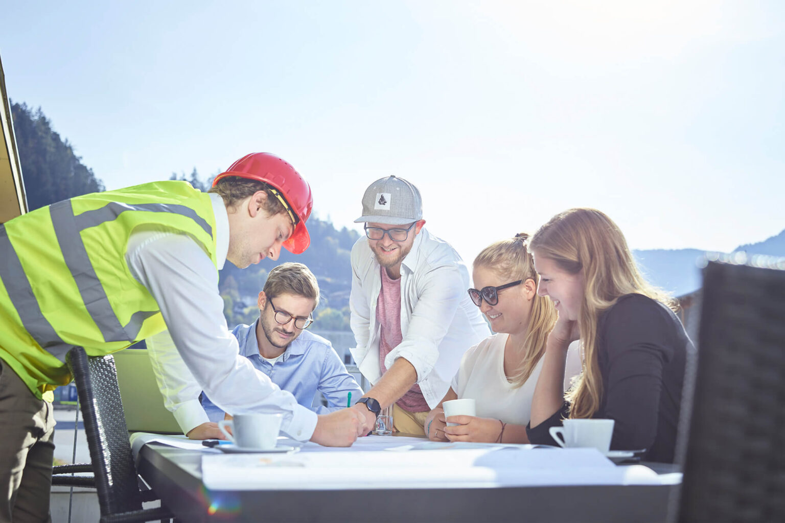 Mehrere Mitarbeiter versammelt auf der Terrasse und besprechen einen Plan